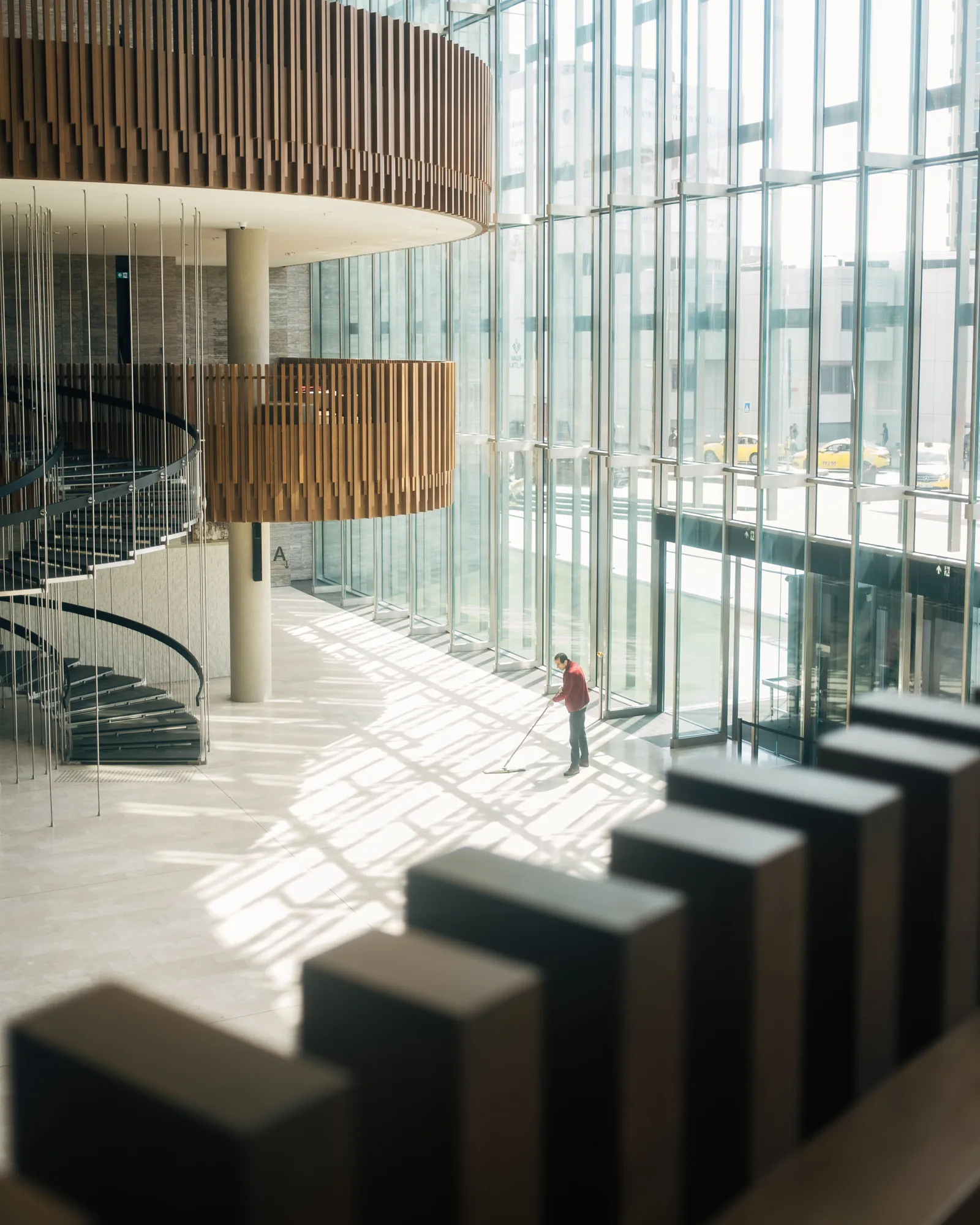 Reinigungskraft bei der Bodenreinigung in der verglasten Eingangshalle eines modernen Gebäudes